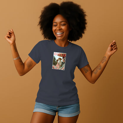 A smiling woman with curly hair wearing a blue t-shirt with a graphic design on it, standing against a beige background.