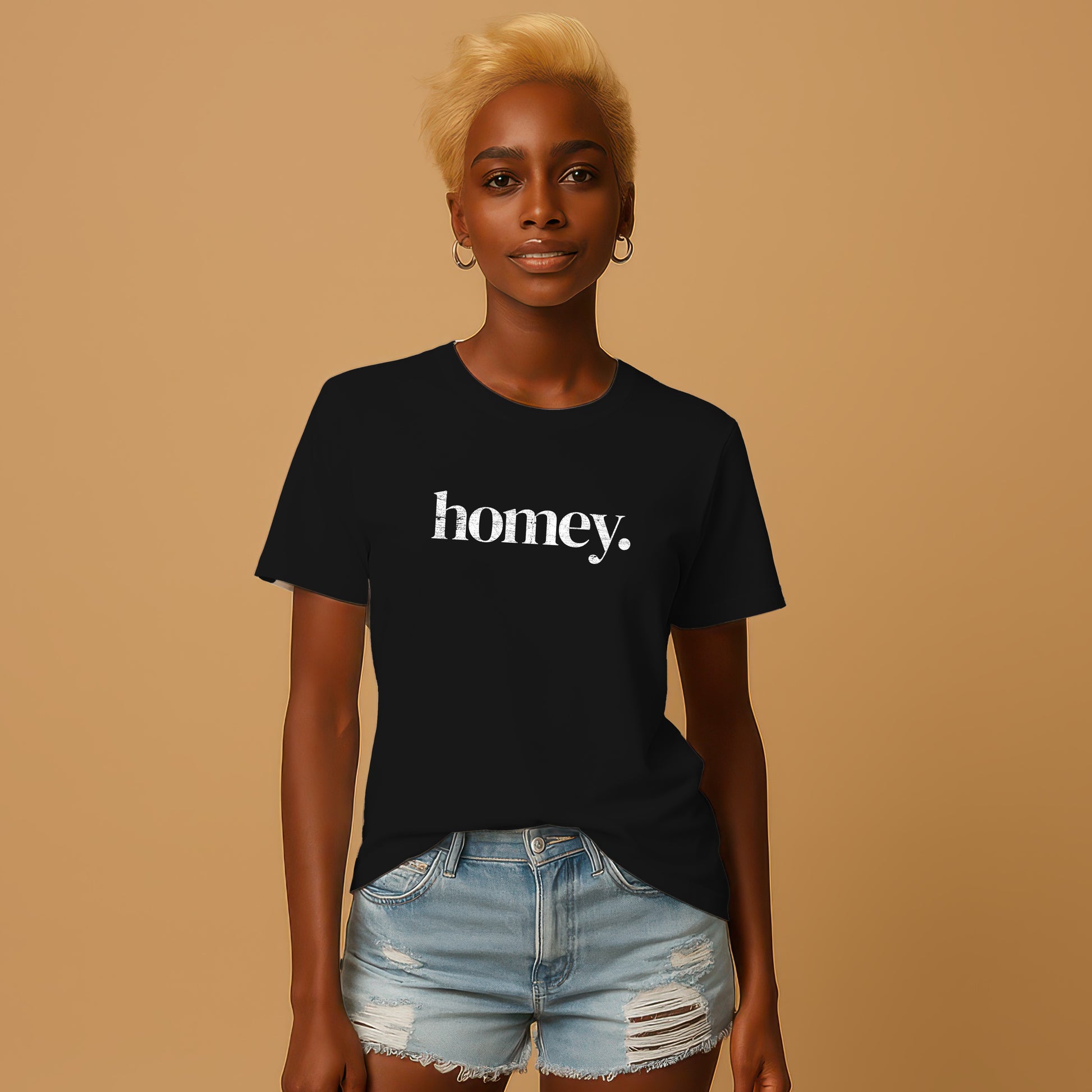 A woman with blonde hair wearing a black t-shirt with the word "honey" printed on it, paired with distressed denim shorts.