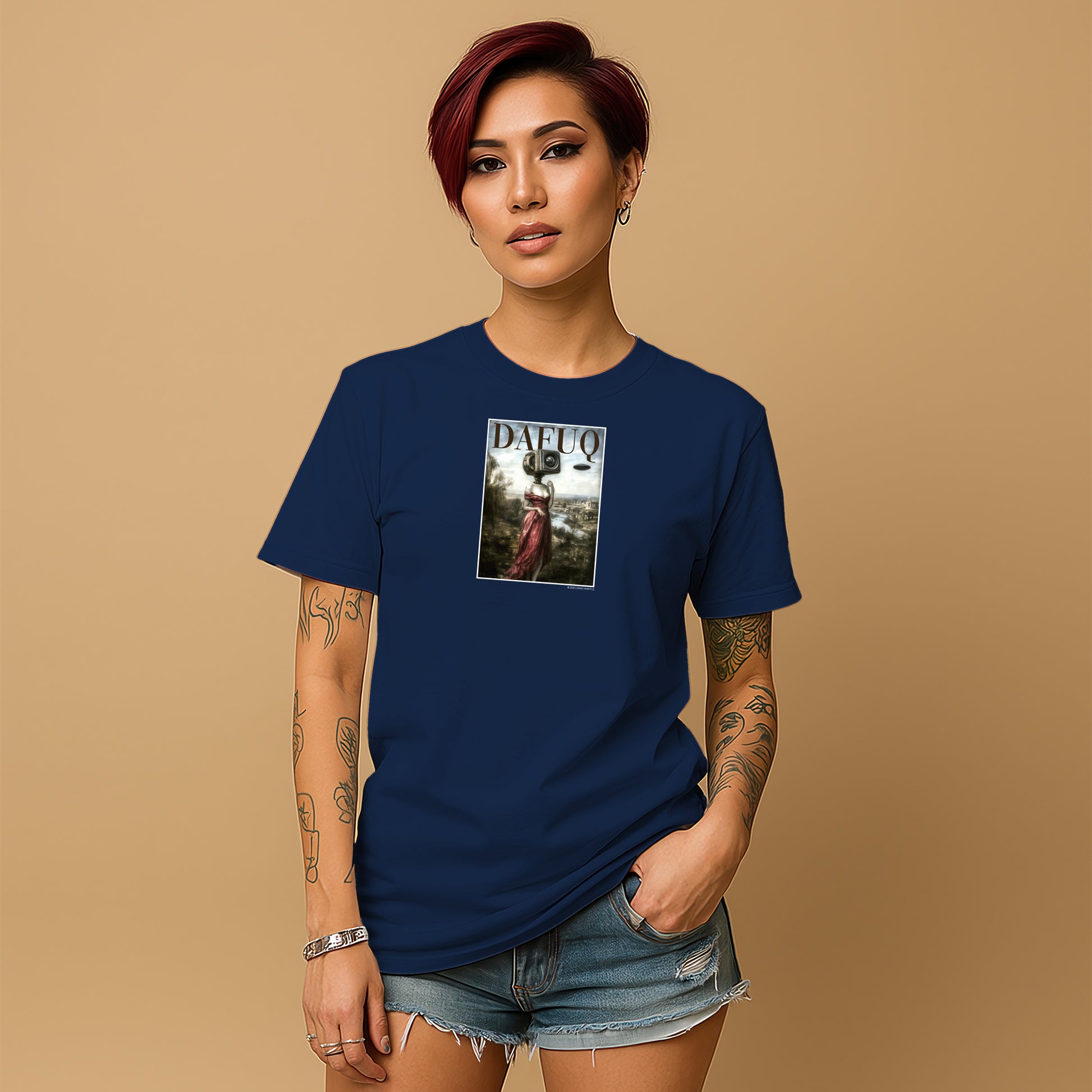 A young woman with short red hair wearing a navy blue t-shirt with a graphic design on it, standing against a beige background.