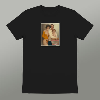 A black t-shirt with a framed photograph of a family, including a woman, a man, and a child, displayed on the front.