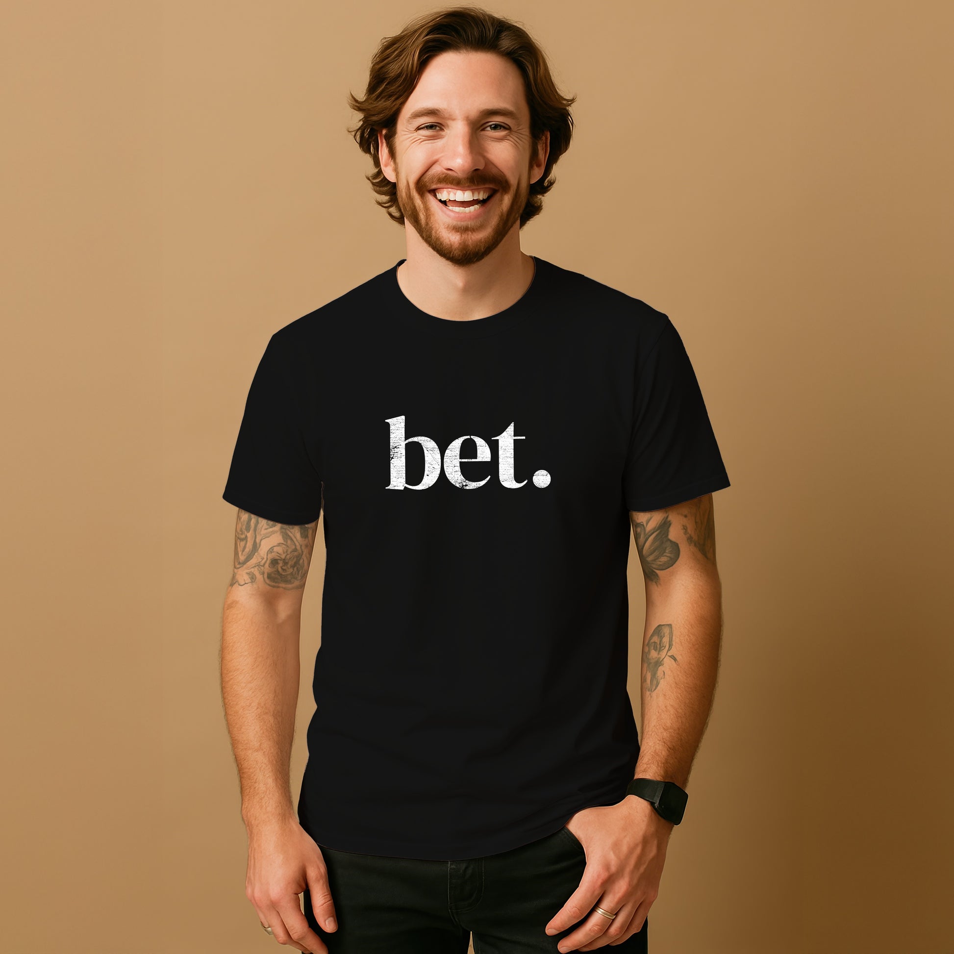 A smiling man with a beard wearing a black t-shirt with the word "bet" printed on it.