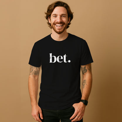 A smiling man with a beard wearing a black t-shirt with the word "bet" printed on it.