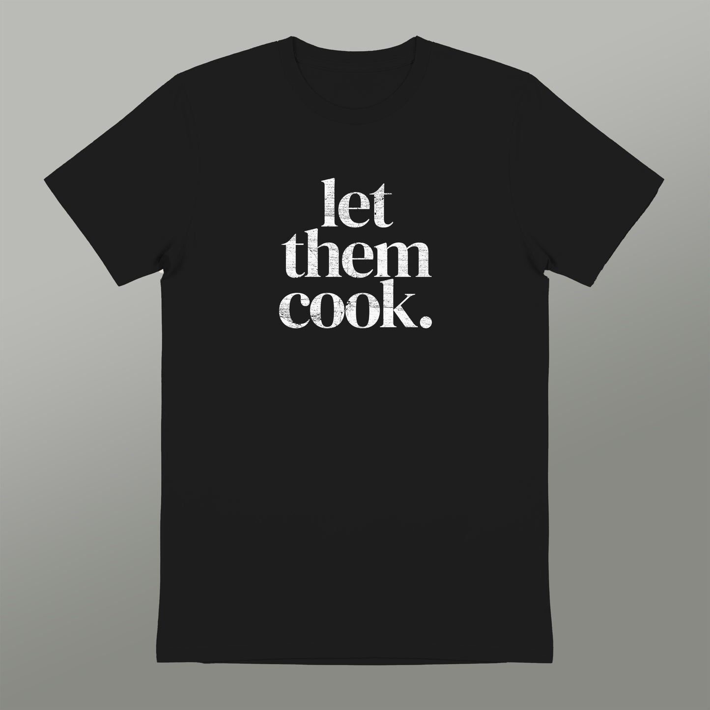 A black t-shirt with the text "let them cook" printed in white on it.