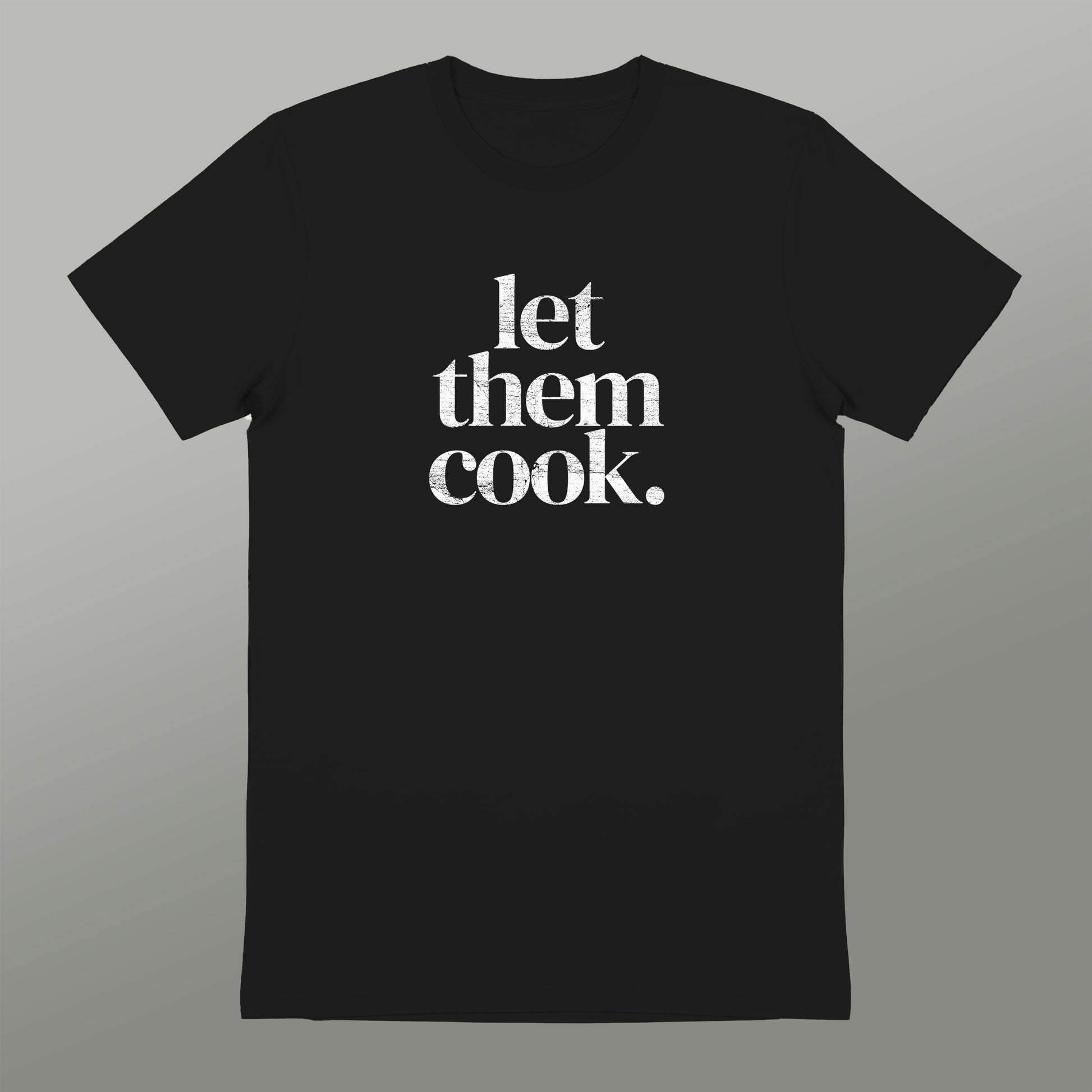 A black t-shirt with the text "let them cook" printed in white on it.